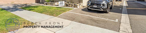 A two-story building with a sign that says "BEACH FRONT PROPERTY MANAGEMENT" in front of it.