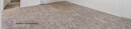 A spacious room with a carpeted floor and a door on the right side.