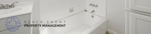 A white bathroom with a tub, sink, and window.