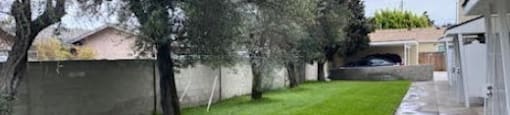 a yard with grass and trees next to a house