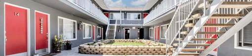 a courtyard between two apartment buildings with stairs and a flower bed