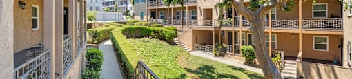 A sunny day at a residential complex with a tree in the foreground.