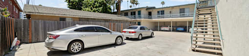 A white car is parked in a lot with a building in the background.