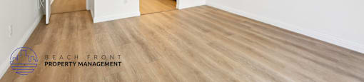 A spacious room with wooden floors and white walls, with a doorway leading to another room.