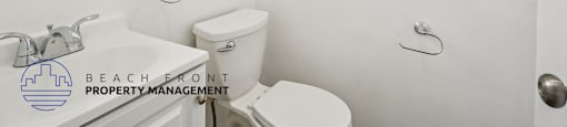 A white bathroom with a toilet, sink, and window.