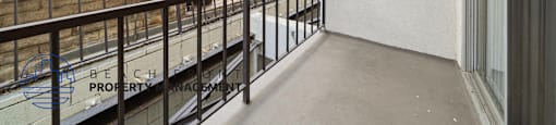 A balcony with a metal railing and a white wall with a window.