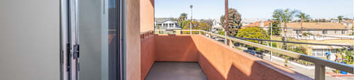 A balcony with a glass door and a view of the street below.