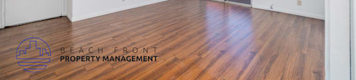 A room with wooden floors and a logo for Beach Front Property Management.