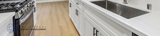 A kitchen with white cabinets and a stainless steel sink.