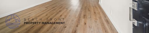 A long, empty hallway with a logo for Beach Front Property Management in the bottom left corner.