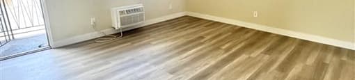 A room with wooden flooring and a window with blinds.