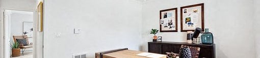 A room with a desk and a fan.