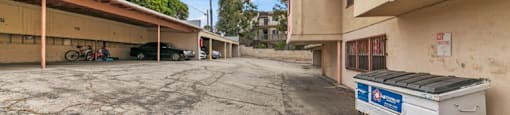 a parking lot with a dumpster in front of a building