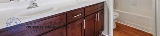 A bathroom with a large mirror, double sink, and wooden cabinets.