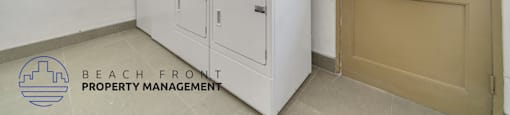 a laundry room with two washing machines and a door to the beach