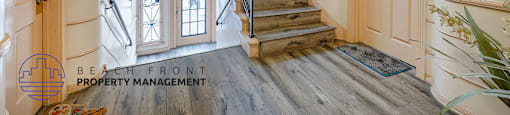 A staircase with a wooden handrail and a rug on the floor.