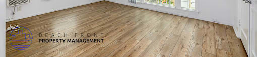 A spacious room with wooden flooring and a ceiling fan.