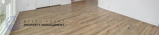 A spacious room with wooden flooring and a ceiling fan.