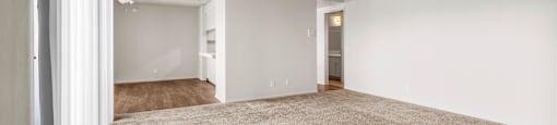 A spacious room with carpeted floor and white walls.