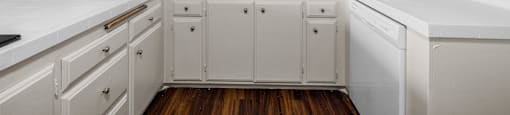 A kitchen with white cabinets and a white countertop.