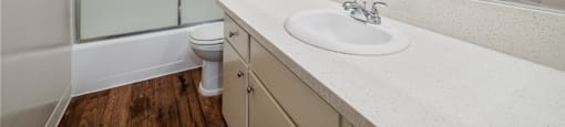 A white sink in a bathroom with a toilet and a walk in shower.