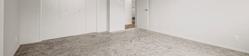 A spacious room with carpeted floor and white walls.