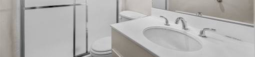 A white bathroom with a toilet, sink, and shower.