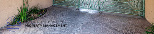 A view of a gate and a wall with a sign that says Beach Front Property Management.