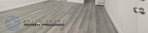A spacious room with wooden flooring and a logo for Beach Front Property Management.