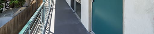 A long, narrow hallway with a green door at the end.