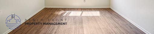 A room with a window and a logo for Beach Front Property Management on the floor.