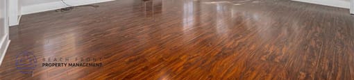 A spacious room with wooden floors and a ceiling fan.