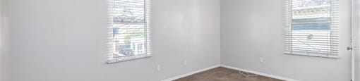 A room with a ceiling fan and two windows.