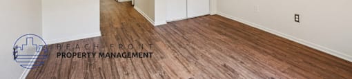 A room with wooden floors and white walls, with a logo for Beach Front Property Management in the bottom left corner.