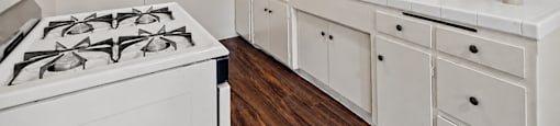 A white kitchen with a stove and cabinets.