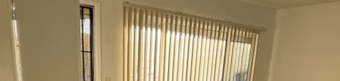 A room with a white door and a window with blinds.