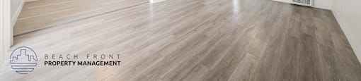 A spacious room with wooden flooring and a ceiling fan.