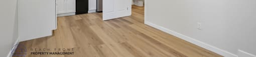 A kitchen with white cabinets and a wooden floor.