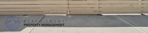 A building with a fence in front of it and the words "Beach Front Property Management" on the fence.