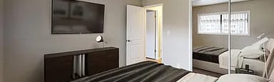 A bedroom with a large bed and a television on the wall.