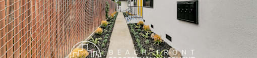 a side view of a building with a sidewalk and a brick wall
