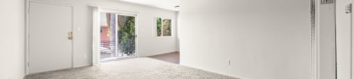 A spacious room with a grey carpet and white walls.