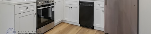 A kitchen with white cabinets and a stainless steel refrigerator.
