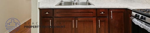 A kitchen with wooden cabinets and a marble countertop.