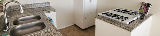 A kitchen with a granite countertop and stainless steel sink.