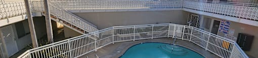 A swimming pool surrounded by a white fence and palm trees.