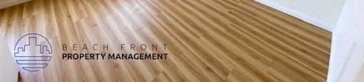 an empty room with wood flooring and a window