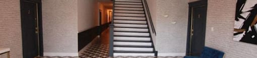 the lobby of a building with a staircase and a checkered floor