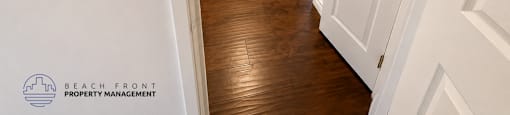 A hallway with white doors and wooden floors.