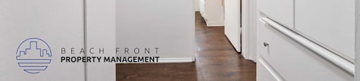 A hallway with white doors and a logo for Beach Front Property Management.